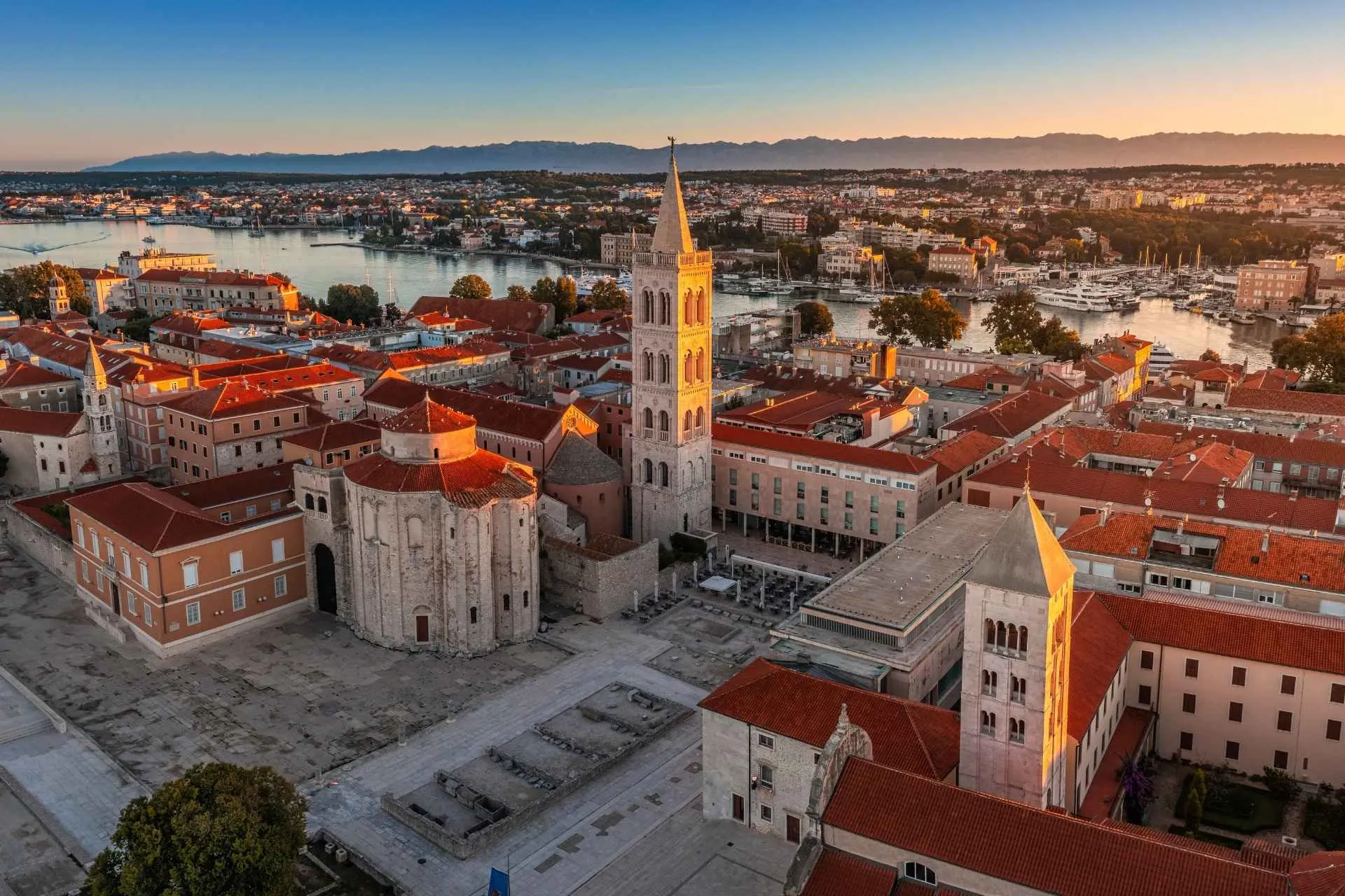 Luchtpanorama van het Forum van de oude stad van Zadar met de Sint-Donatuskerk en de klokkentoren van de Kathedraal van Sint-Anastasia op een zomerochtend tijdens een gouden zonsopgang, Zadar, Kroatië | de Jong Intra Vakanties