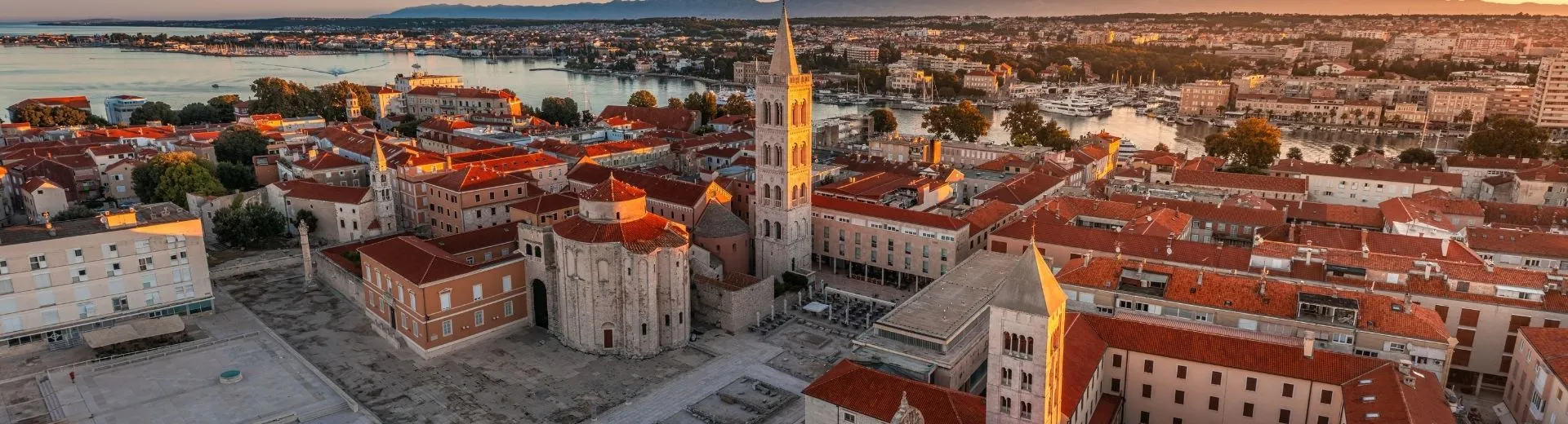 Luchtpanorama van het Forum van de oude stad van Zadar met de Sint-Donatuskerk en de klokkentoren van de Kathedraal van Sint-Anastasia op een zomerochtend tijdens een gouden zonsopgang, Zadar, Kroatië | de Jong Intra Vakanties
