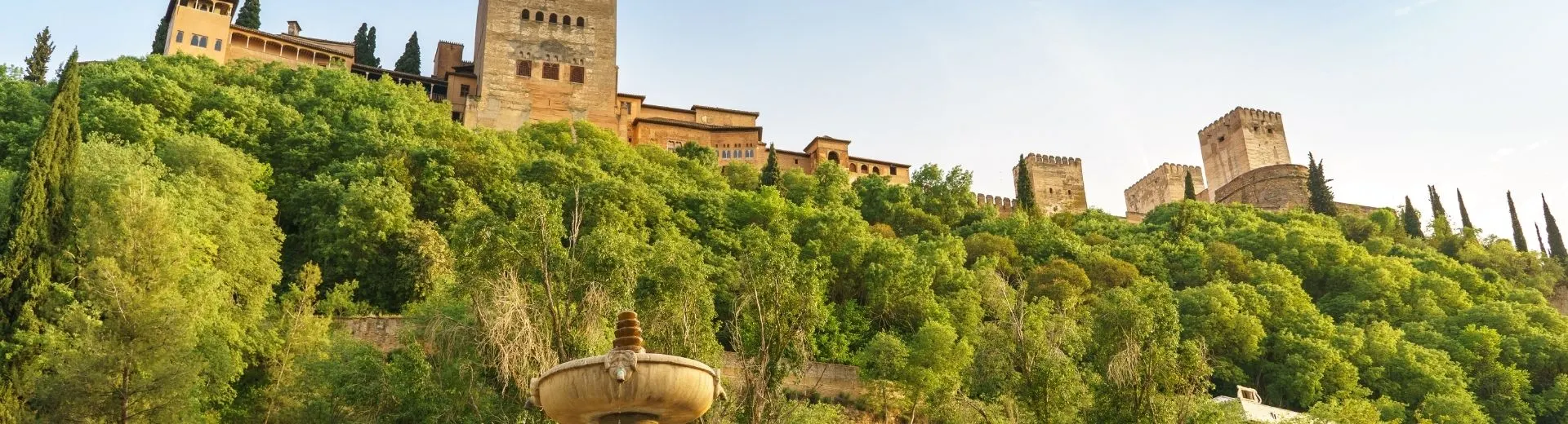 Alhambra, wereldberoemd monument van Granada, gezien vanaf de oever van de rivier de Genil met een fontein, Granada, Andalusië, Spanje | de Jong Intra Vakanties

