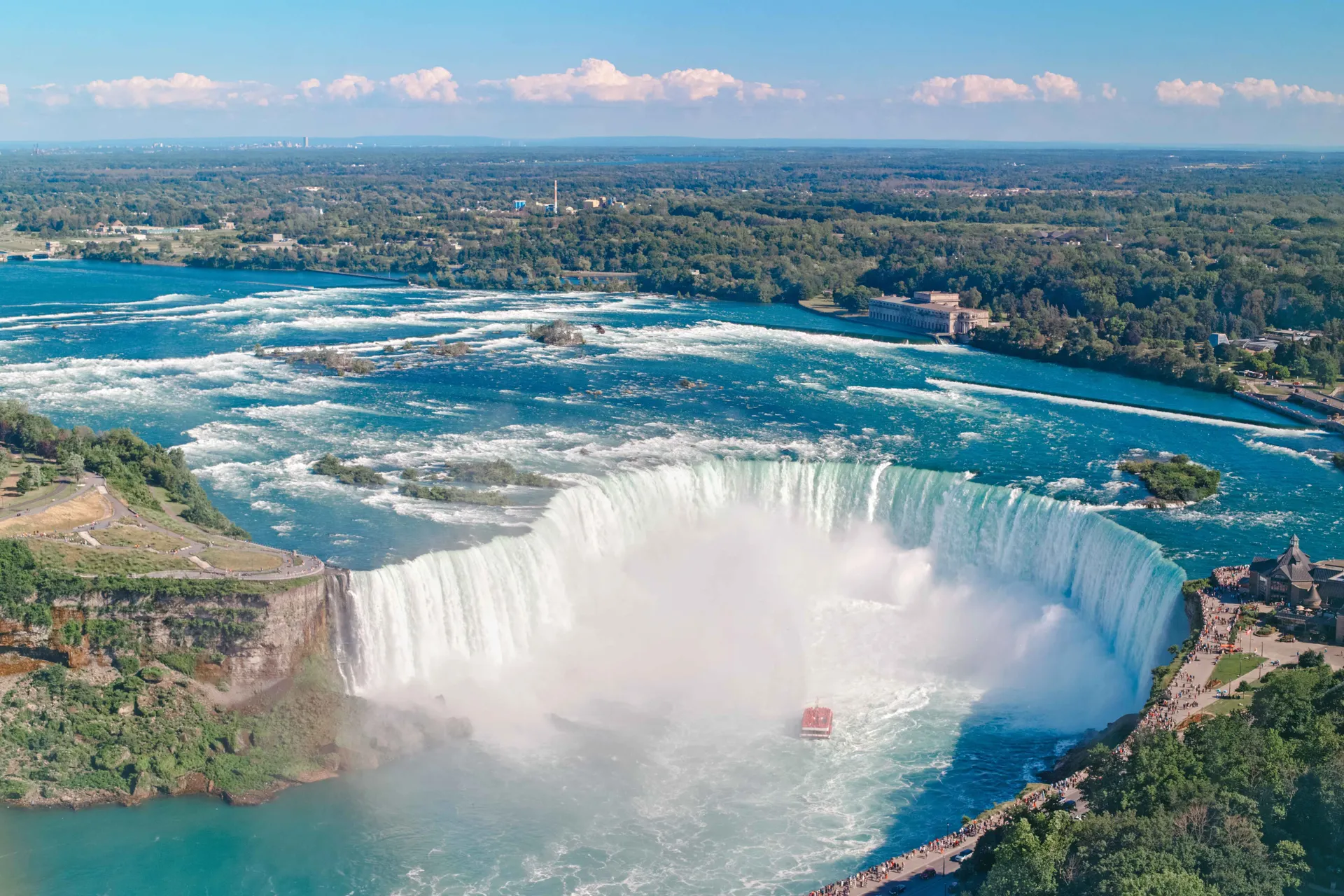 Luchtfoto van het landschap van de Niagara Falls tussen de Verenigde Staten en Canada. De hoefijzervormige Canadese waterval op een zonnige dag. Rondvaartboot bij deze beroemde toeristische trekpleister | de Jong Intra Vakanties