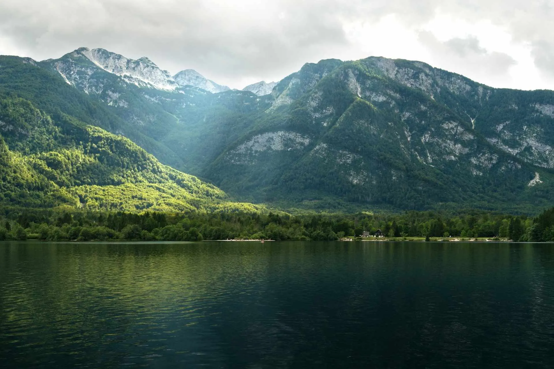 Zonnestralen door een bewolkte hemel op het rustige Bohinjmeer, Slovenië | de Jong Intra Vakanties
