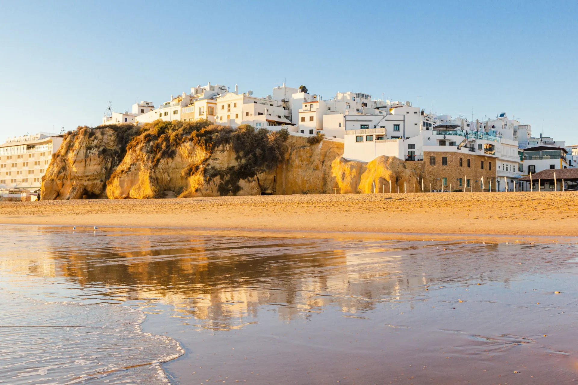 White Albufeira town in Algave coast in Southern Portugal, beautiful scenic white buildings on sandy cliff near perfect yellow sand beach